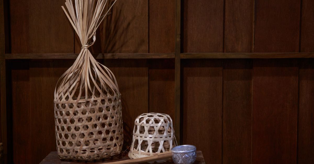 Cesta tejida con fibra vegetal sobre una mesa junto a muestras de fibras naturales